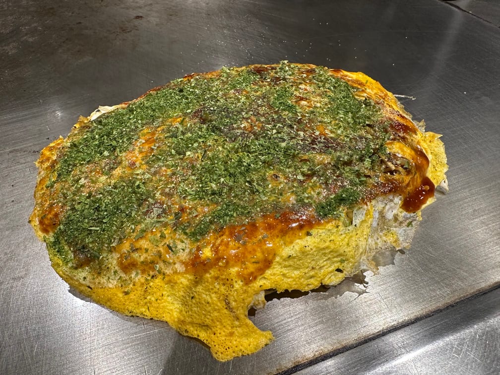 철판에 올라와 있는 오코노미야끼의 사진.