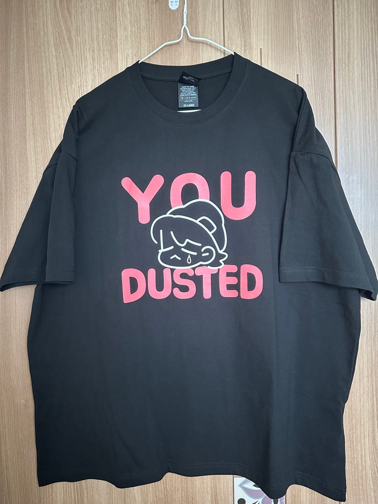 YOU DUSTED라는 붉은 글자와 시무룩한 캐릭터가 그려진 도안이 그려진 검은 티셔츠.