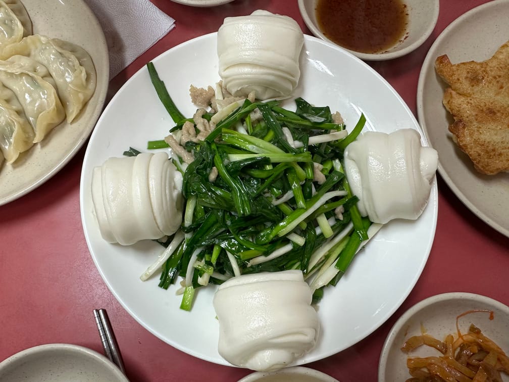 그릇에 부추잡채와 꽃빵이 차려진 모습. 찐만두, 군만두, 자차이, 간장 종지 등도 보인다.