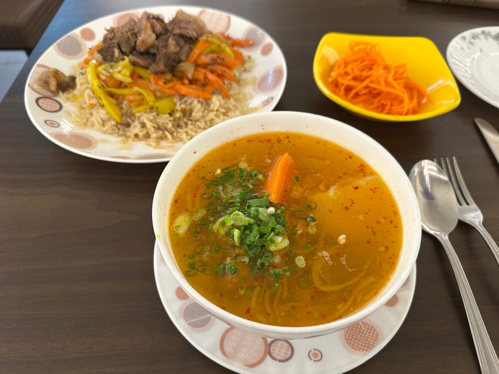 붉고 투명한 당근, 감자, 채썬 파가 보이는 국물 요리, 인디카 쌀밥에 당근과 노란 양파, 고기가 올라간 밥 요리, 당근 김치가 차려진 식탁.