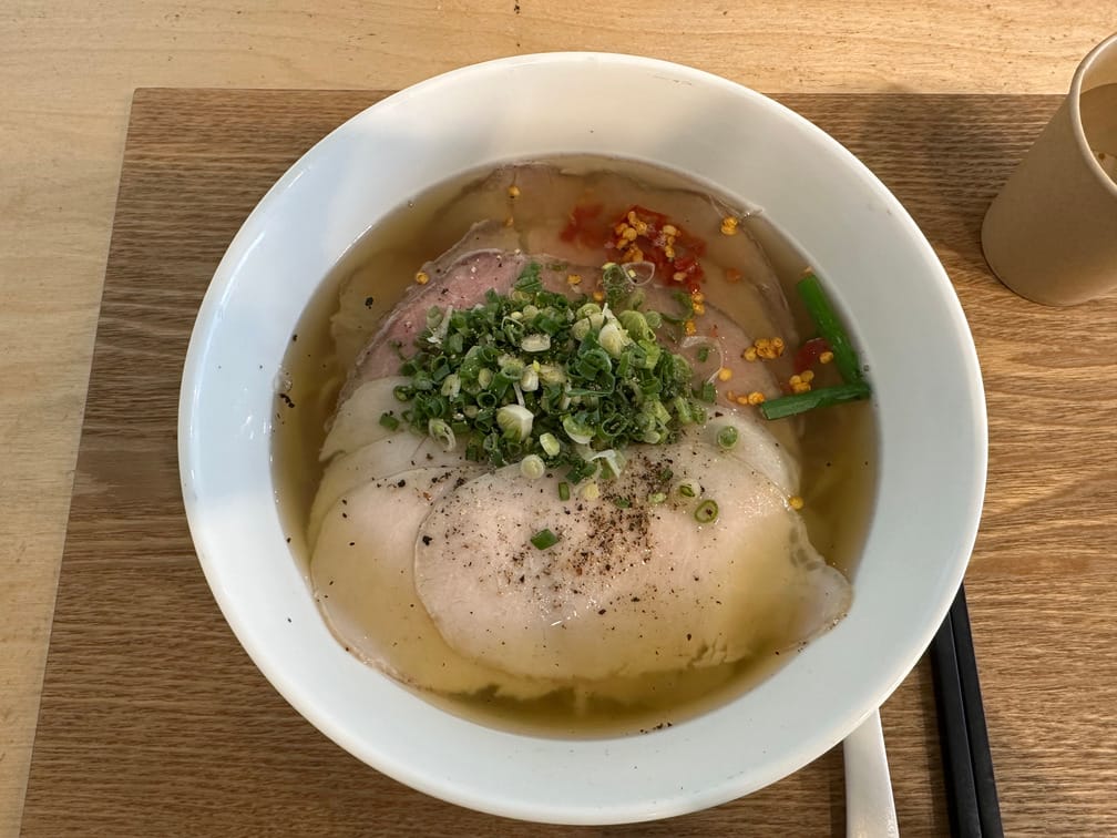 흰 그릇에 맑은 국물, 채썬 파, 붉고 흰 얇은 고기, 반쯤 풀린 고춧가루로 된 음식이 차려져 있다.