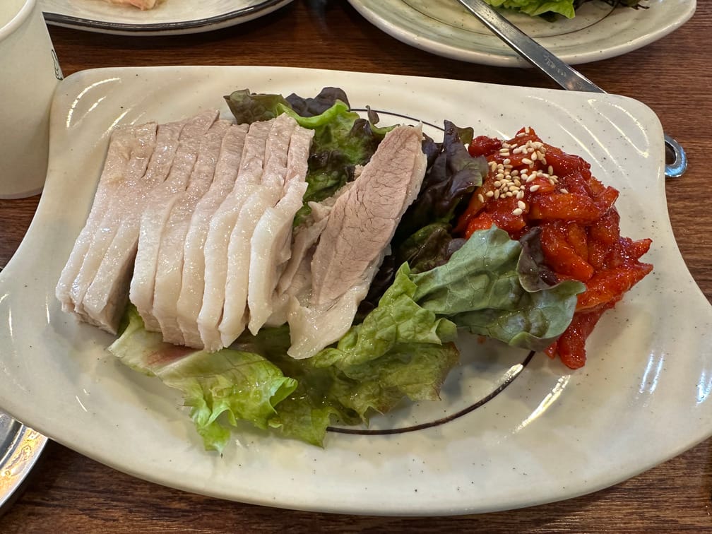 그릇에 깔린 상추 위에 썰린 한 뭉치의 항정살, 무김치의 사진.